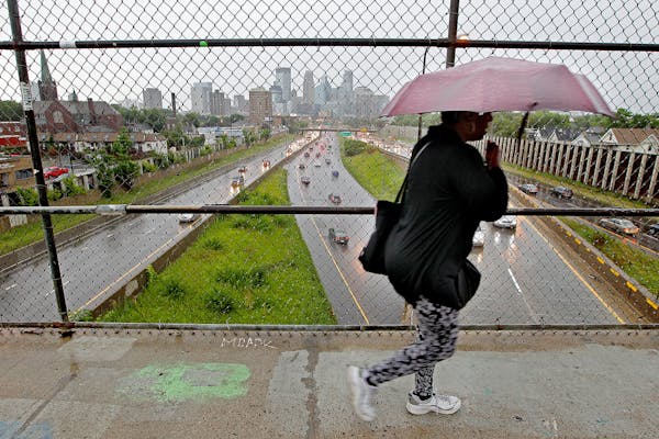 A pedestrian made her way across the E. 24th Street walking bridge as the rain came down over Minneapolis, Tuesday, July 28, 2015 in Minneapolis, MN.