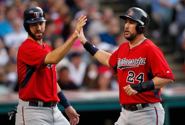 Minnesota Twins' Trevor Plouffe (24) is congratulated by teammate Joe Mauer after scoring on a single by Tori Hunter during the third inning of a base
