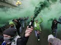 Members of the Emerald City Supporters burn smoke devices as they take part in the traditional "March to the Match" before the Seattle Sounders face S