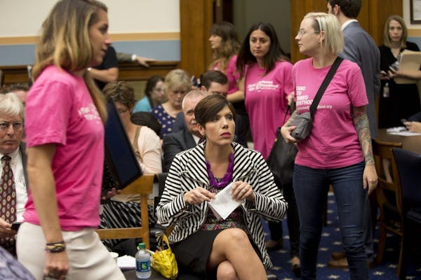 As supporters of Planned Parenthood looks for seats, Melissa Ohden, center, an anti-abortion activist from Gladstone, MO., waits to testify before the