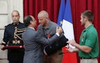 French President Francois Hollande hugs U.S. Airman First Class Spencer Stone, while Oregon National Guard Spc. Alek Skarlatos applauds, after they we