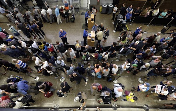 In this Tuesday, Aug. 11, 2015 photo, travelers wait in long security lines at Seattle-Tacoma International Airport, in Seattle.