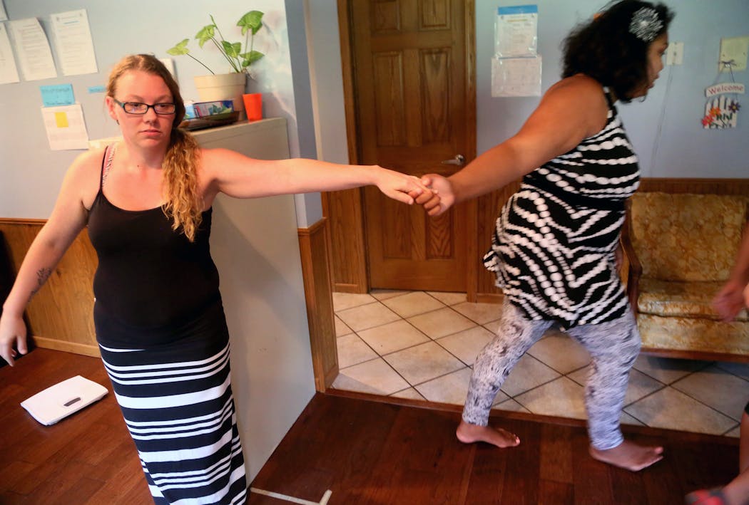 Ashley Daly tugs on staff member Amber Johnson at a group home in Hermantown, near Duluth.