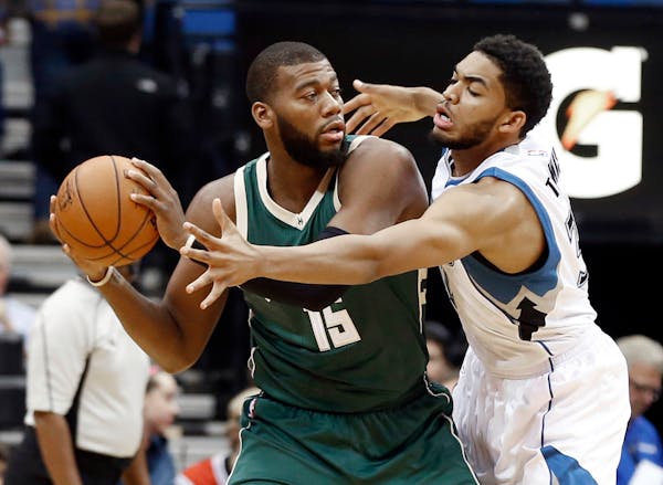 Karl-Anthony Towns, right, tries to get to the ball held by Milwaukee Bucks' Greg Monroe in the first half of an NBA preseason game, Friday, Oct. 23, 