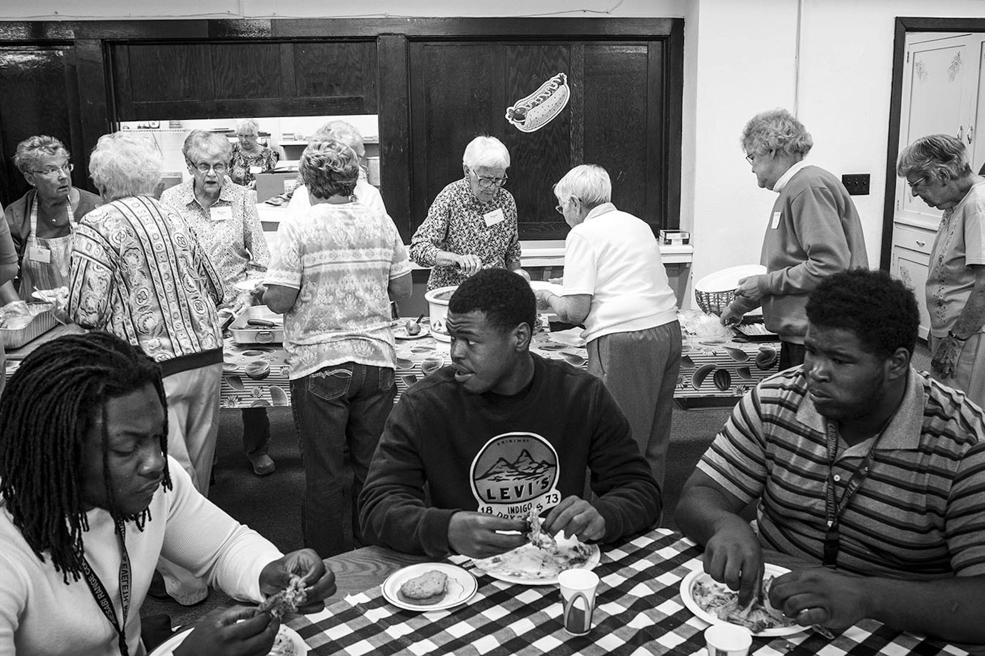 From left, linebacker Elvin Turner, receiver Shaheem Sanders and lineman Uriah English ate lunch in the basement of Hope Community Presbyterian Church in late August as church volunteers served themselves after feeding the team.