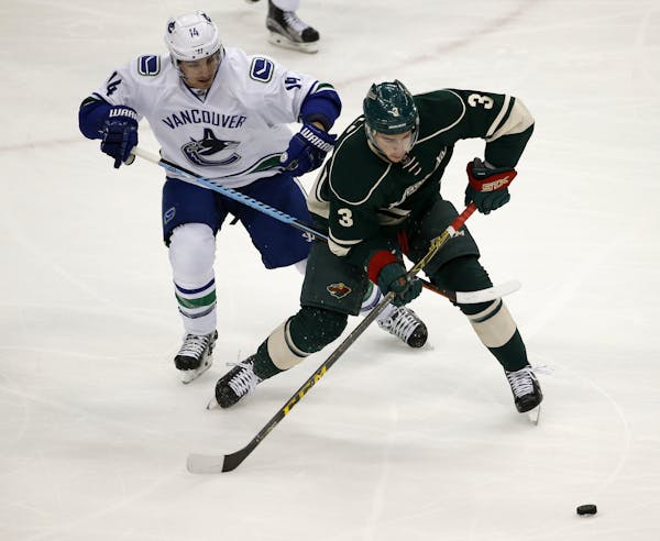 The Wild’s Charlie Coyle and Vancouver’s Alex Burrows chased the puck during the first period of their game Wednesday night at Xcel Energy Center.