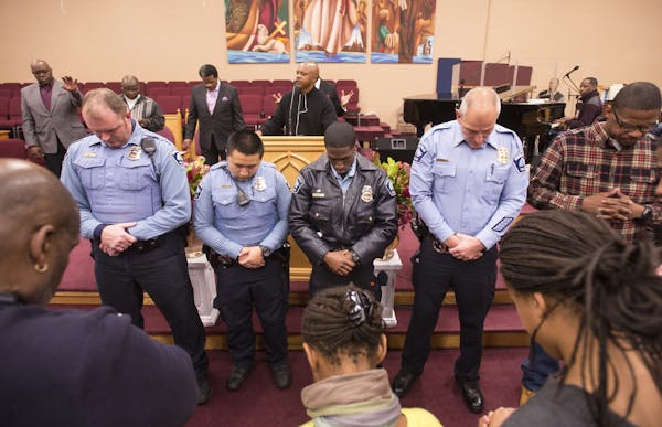 From left, Fourth Precinct police officers Will Gregory, Roger Moua, Xavier Rucker and Inspector Mike Friestleben, bowed their heads during a prayer l