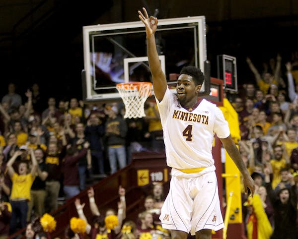 The University of Minnesota's Kevin Dorsey Jr. (4) signals a three after hitting a three-point shot in overtime and putting the U of M up by 6 during 