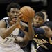 Minnesota Timberwolves guard Andrew Wiggins (22) looks to pass to a teammate under pressure from Indiana Pacers forward Paul George, right, during the