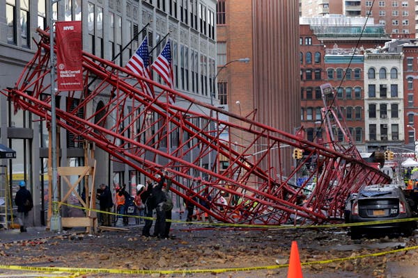 Officials survey the scene of a crane collapse in New York, Friday, Feb. 5, 2016. The crane landed across an intersection and stretched much of a bloc