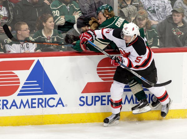 Minnesota Wild center Mikael Granlund, of Finland, is driven hard into the boards by New Jersey Devils defenseman Adam Larsson (5), of Sweden, during 