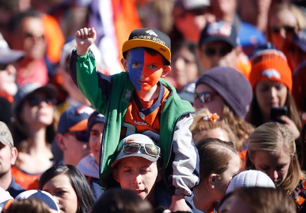 A young boy has his face painted in the colors of the Denver Broncos as he looks on at a rally following a parade through downtown Tuesday, Feb. 9, 20