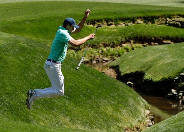 Jordan Spieth jumps over a creek on the 13th fairway during a practice round for the Masters golf tournament, Monday, April 4, 2016, in Augusta, Ga. (