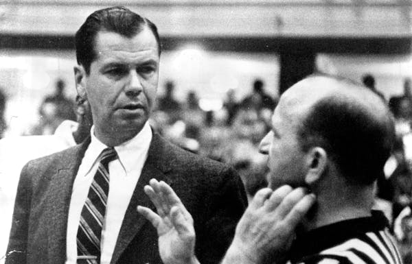 John Kundla, talking with NBA referee Sid Borgia during a game in 1959, was initially reluctant to take the Lakers coaching job, but he was finally pe