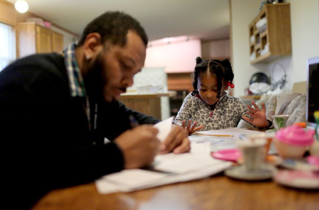 Kendrick Bates finished his final assignment for a course he is taking at Martin Luther College in New Ulm while his daughter worked on her math homework from their trailer in Hanska, Minn. He is among those struggling to find affordable housing in suburban areas.