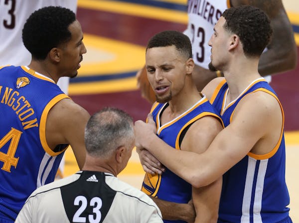 Golden State Warriors guard Stephen Curry is held back from referee Jason Phillips (23) by Shaun Livingston, left, and Klay Thompson, right, while rea