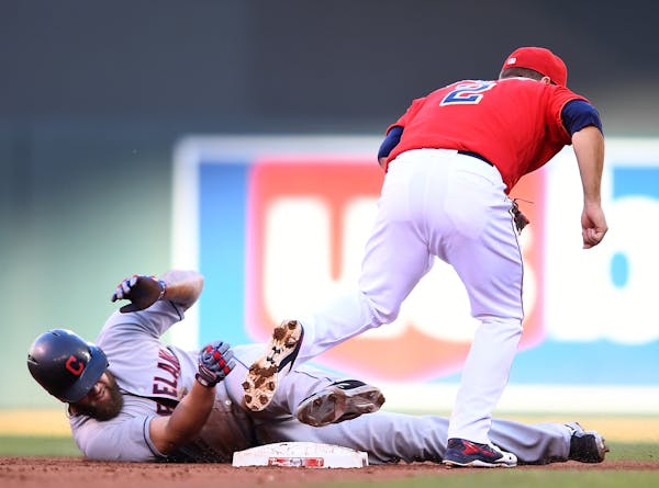 Cleveland Indians first baseman Mike Napoli (26) slid past first after being tagged out by Minnesota Twins second baseman Brian Dozier (2) after nearl