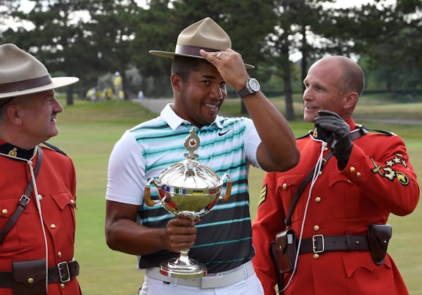 Jhonattan Vegas, of Venezuela, holds the trophy as he adjusts a Stetson borrowed from a Mountie, after his victory in the Canadian Open golf tournamen