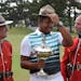Jhonattan Vegas, of Venezuela, holds the trophy as he adjusts a Stetson borrowed from a Mountie, after his victory in the Canadian Open golf tournamen