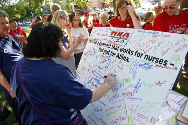 A nurse adds her signature to scores of signatures that fill a large poster of the Minnesota Nurses Associations as community, labor leaders and faith