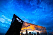 U.S. Bank Stadium’s glass facade reflects filtered twilight through a smoky blue sky.