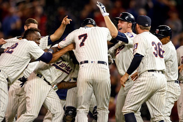 Teammates surround Minnesota Twins' Joe Mauer (7) after he hit in Brian Dozier to defeat the Cleveland Indians in twelve innings at a baseball game Sa