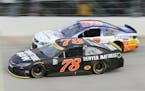 Martin Truex Jr., (78) drives past Timmy Hill (98) during a NASCAR Sprint Cup series auto race, Sunday, Oct. 2, 2016, at Dover International Speedway 