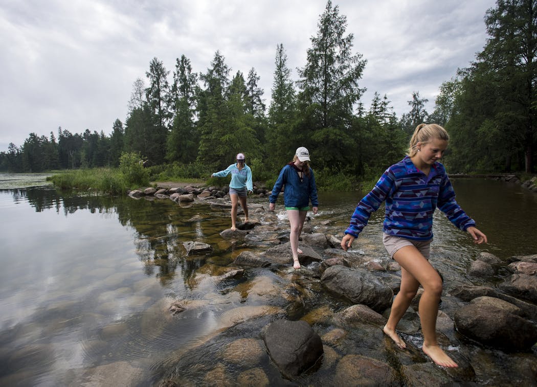Emma Daniels, from right, Abby MacFarlane and Marie Preston walked across the rocks at the headwaters of the Mississippi at Lake Itasca.