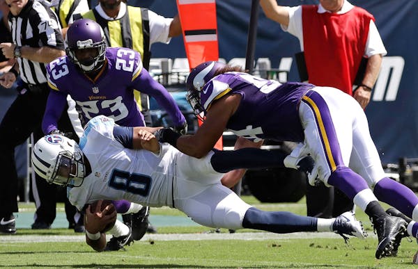 Tennessee Titans quarterback Marcus Mariota (8) is brought down by Minnesota Vikings defenders Eric Kendricks (54) and Terence Newman (23)