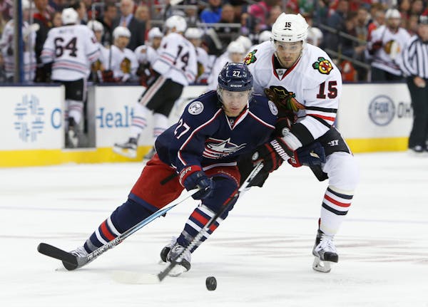 Columbus Blue Jackets' Ryan Murray, left, tries to move the puck past Chicago Blackhawks' Artem Anisimov, of Russia, during the first period of an NHL