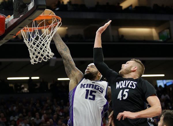 Sacramento Kings center DeMarcus Cousins, left, goes up for a dunk against Minnesota Timberwolves center Cole Aldrich during the second half of an NBA