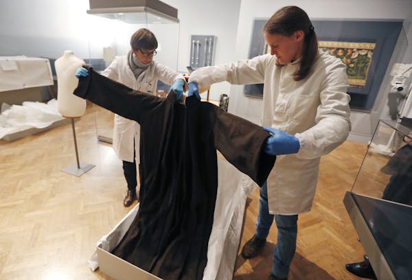 Unpacking the past: German conservators Eva Düllo, left, and Andrea Knüpfer, took out a 16th-century monk’s robe Thursday for the exhibit.