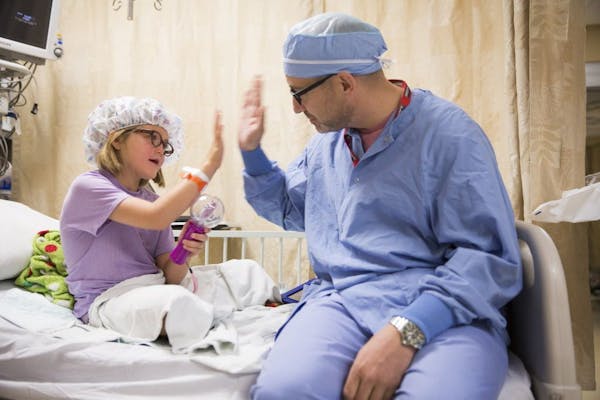 FILE -- Reagan Lennes, 6, high fives with Lance Svoboda, an oral and maxillofacial surgeon at HCMC, who performed most of her surgeries after she was 