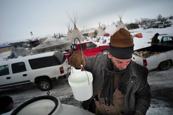 Jonathan Shields, who is from Portland, helped fill some containers with water using a bucket because it was partially frozen and would not flow throu
