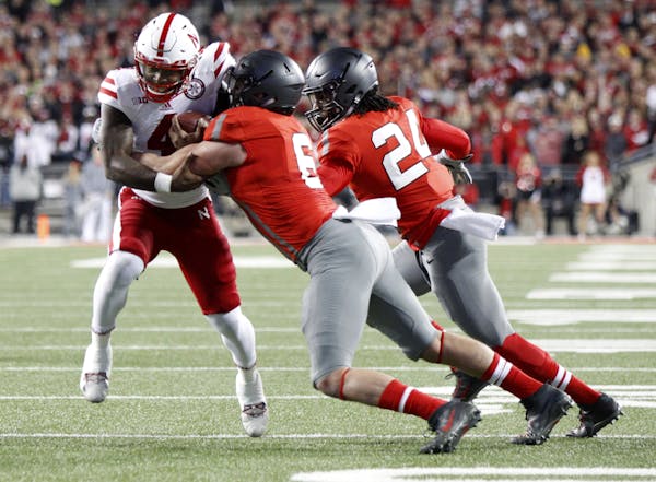 Nebraska quarterback Tommy Armstrong, left, tries to get past Ohio State defender Gareon Conley, center, and Malik Hooker
