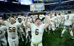 Totino-Grace fullback Brady Bertram (6) celebrated with his team's Class 6A championship trophy Friday night after defeating Eden Prairie 28-20 at the