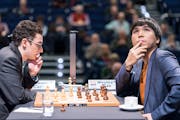 Grandmaster Wesley So, right, checks the status of other games being shown on a video screen at the London Chess Classic on Saturday, as his opponent 