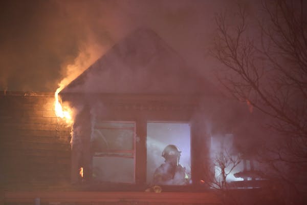 A firefighter works to extinguish a fire Monday night on the third floor of a building on Aldrich Avenue South in Minneapolis, Minn. while flames stil