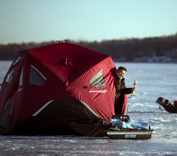 Tay Xiong held a northern pike he caught while ice fishing Wednesday on White Bear Lake. His portable shelter provided him comfort.