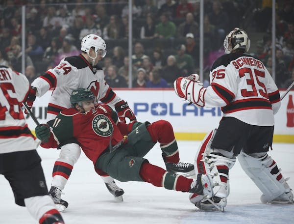 Minnesota Wild left wing Zach Parise (11) went down in front of New Jersey Devils goalie Cory Schneider while fighting for position with Devils defens