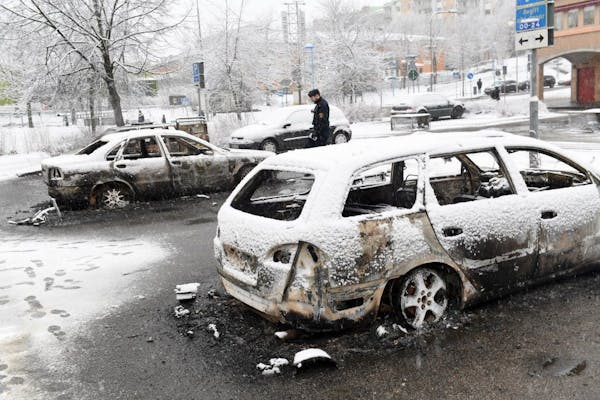 In this picture taken on Monday, Feb. 20, 2017,a policeman investigates a burned out car in the suburb of Rinkeby outside Stockholm. Police in Sweden 