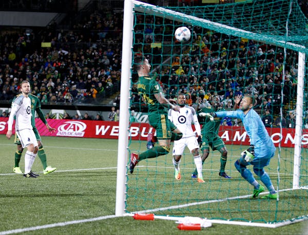 Portland Timbers' Lawrence Olum (13) watches in the background as his shot soars above teammate Liam Ridgewell (24) and into the net for Portland's fi