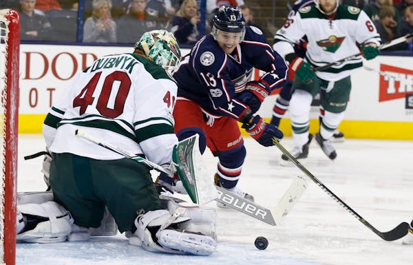 Minnesota Wild's Devan Dubnyk, left, makes a save against Columbus Blue Jackets' Cam Atkinson during the second period of an NHL hockey game Thursday,