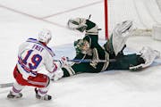 A falling Minnesota Wild goalie Devan Dubnyk, right, blocks a shot by New York Rangers' Jesper Fast during the first period of an NHL hockey game Satu