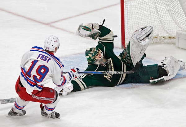 A falling Minnesota Wild goalie Devan Dubnyk, right, blocks a shot by New York Rangers' Jesper Fast during the first period of an NHL hockey game Satu