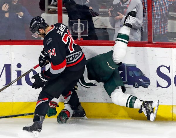 The Carolina Hurricanes' Jaccob Slavin (74) upends the Minnesota Wild's Jason Pominville (29) as he slams him into the boards during the third period 