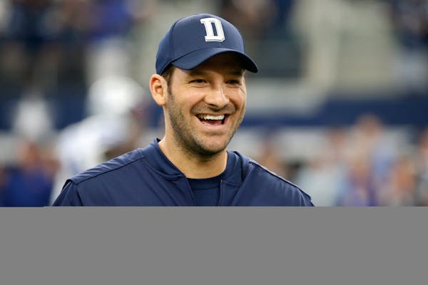 Dallas Cowboys quarterback Tony Romo smiles as he talks with teammates on the field during warm ups before an NFL football game against the Cincinnati