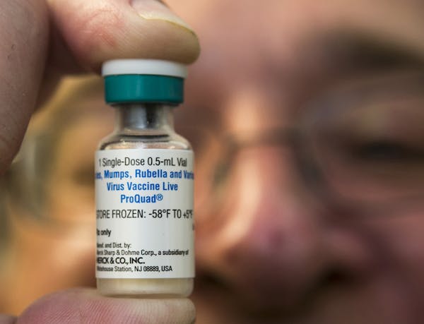 A pediatrician holds a dose of the measles-mumps-rubella (MMR) vaccine. On Friday, the Minneapolis School District said in an e-mail that vaccine is t
