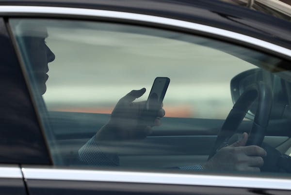 A man uses his cellphone while driving in downtown Minneapolis on Wednesday, a common sight.