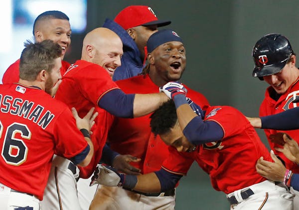 Minnesota Twins' Jorge Polanco, right, is swarmed by teammates after his walk-off sacrifice fly in the 10th inning of a baseball game against the Kans
